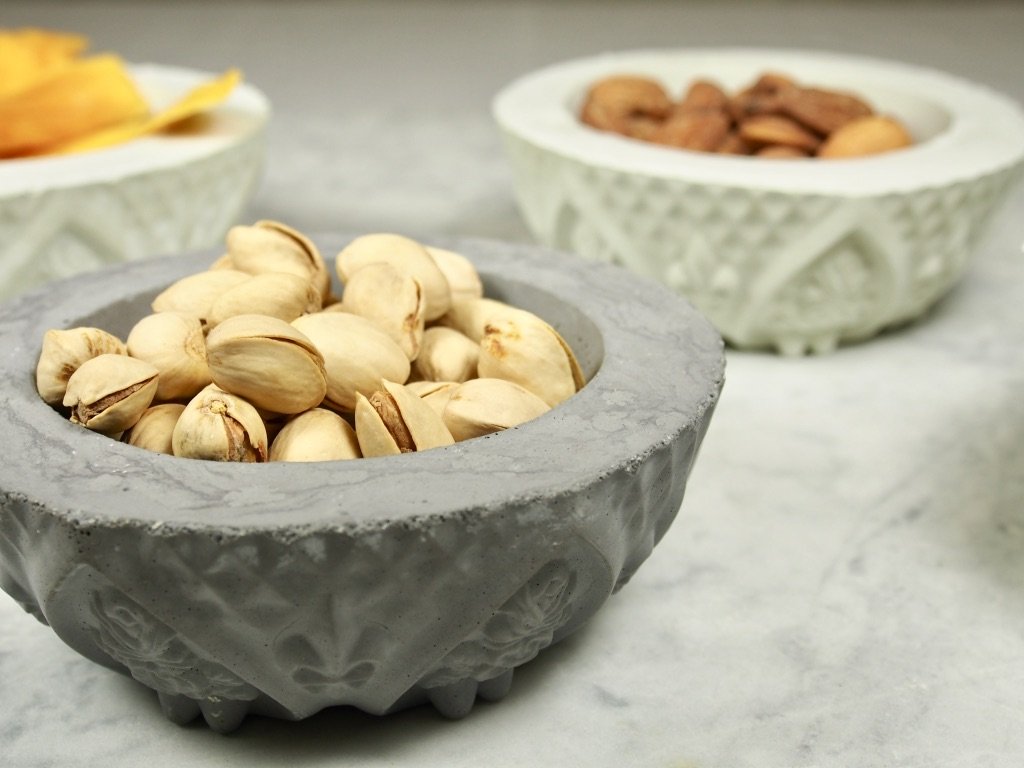 Fleur de lis vintage concrete bowl with party snacks on marble table, modern home decor